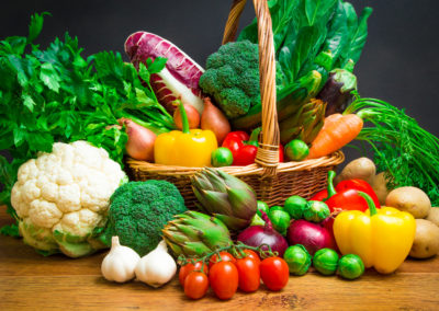 Raw vegetables in wicker basket on wooden table